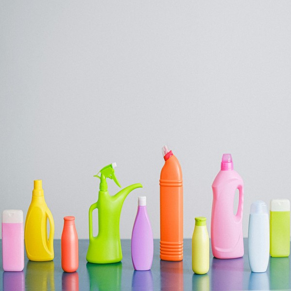 Arrangement of colorful plastic bottles with assorted cleaning products for household placed on table in row against white background in light studio